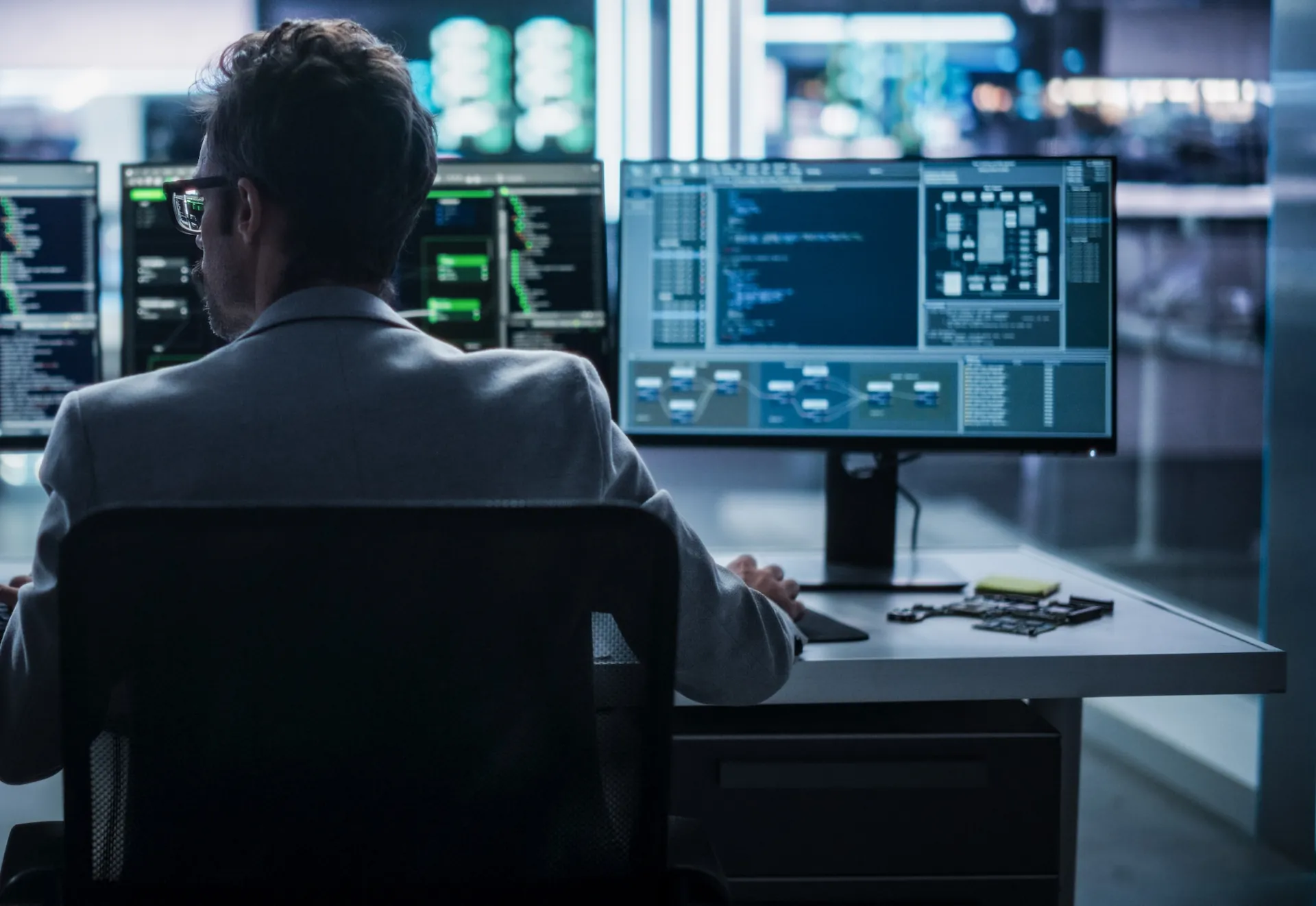 Employee working on project at his desk with multiple monitors